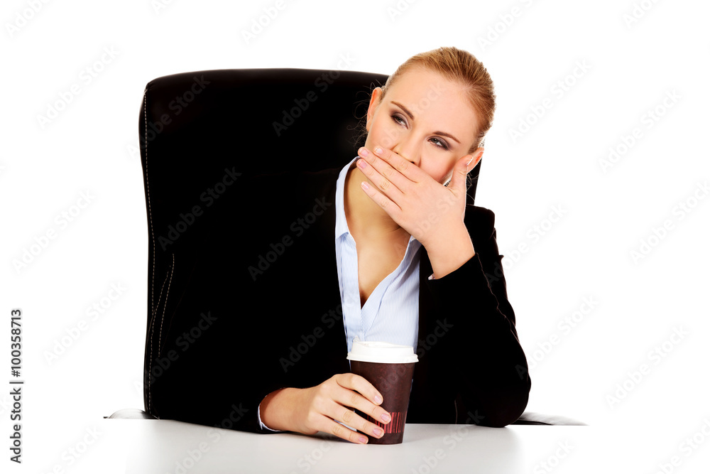 Tired business woman with coffee in paper cup behind the desk Tired business woman with coffee in paper cup behind the desk