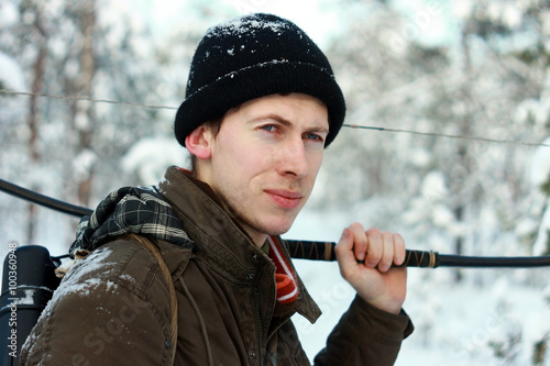 Охотник лучник с луком, стрелами и колчаном в зимнем снежном лесу на охоте