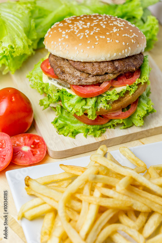 Delicious hamburger and french fries on wooden table