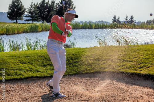 Man playing golf from bunker
