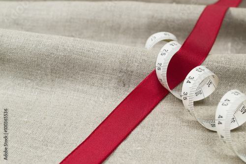 Red tape with measuring tape on a linen cloth
