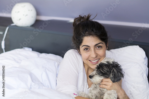 young woman sleeping with her small dog in a human bed. 