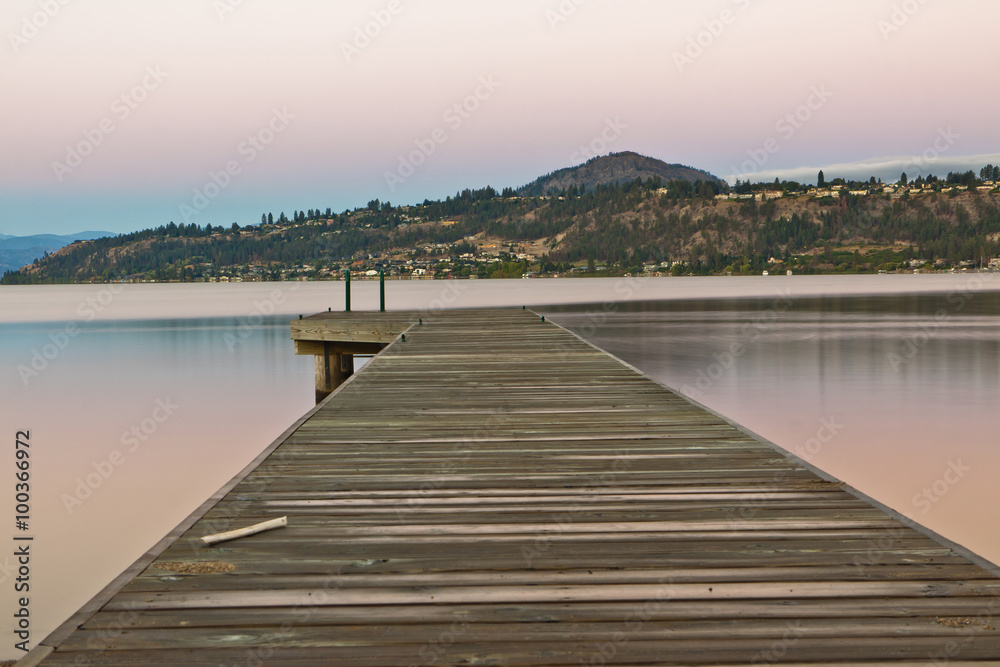 boat dock on still lake at sunrise in mountains