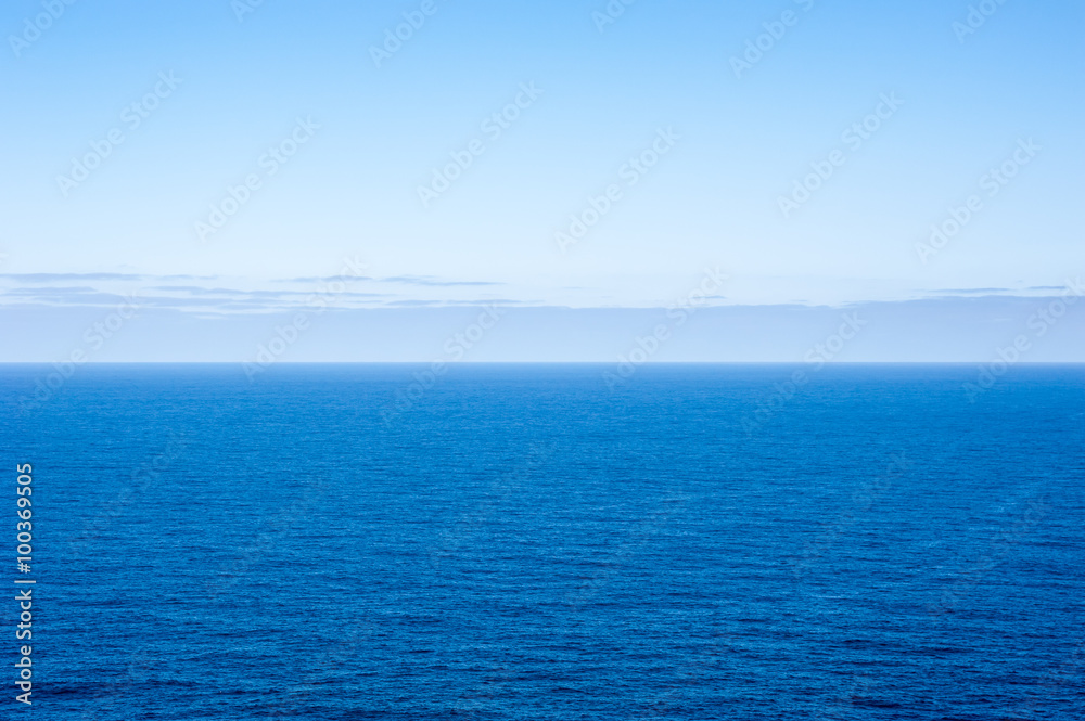 Deep blue empty ocean seascape with clouds on horizon
