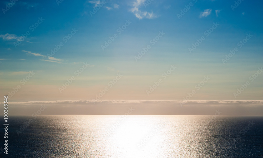 Sunshine on empty ocean with cloud layer and colorful sky