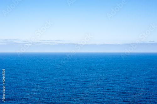 Deep blue empty ocean seascape with clouds on horizon