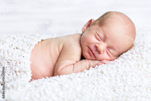adorable newborn boy sleeps on the white blanket with background 