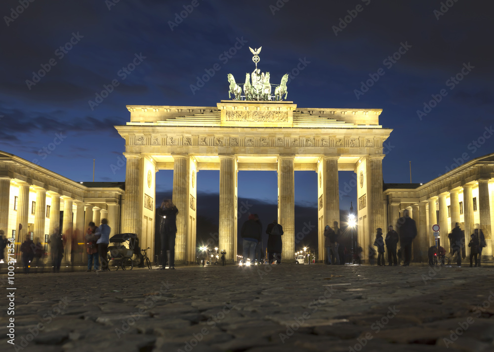 Obraz premium The floodlit Brandenburg Gate in Berlin with a few fleeting shadows of anonymous Berliner's - Symbol of Germany.