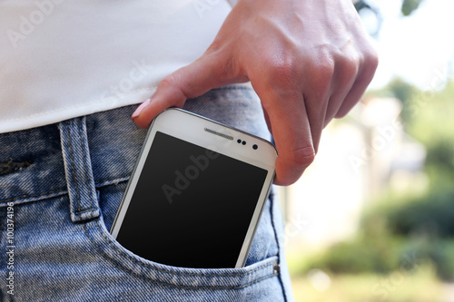 White smart mobile phone in jeans pocket