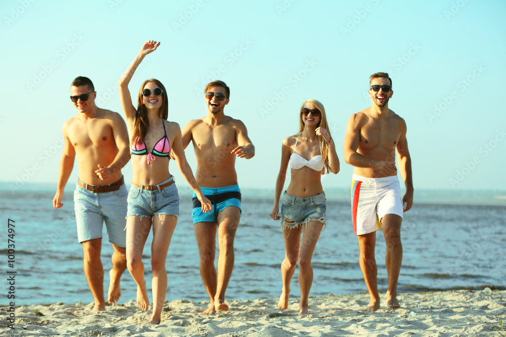 Happy friends running at the beach, outdoors