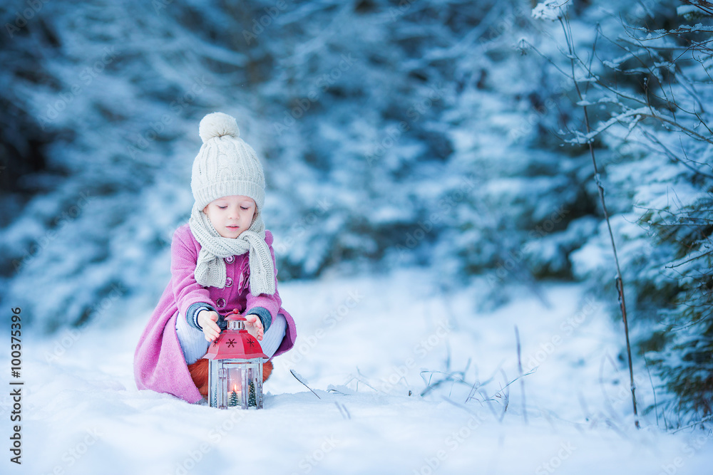 Adorable little girl with flashlight in frozen winter on Christmas outdoors