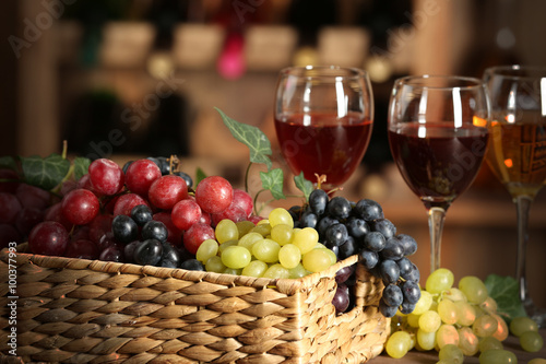 Grape in wicker box on a table on wine bottles background