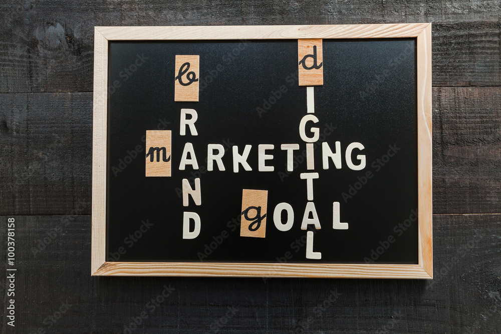 Wooden letters on slate and wood background with a concept message about marketing concept and gearwheels Wooden letters on slate and wood background with a concept message about marketing concept and gearwheels