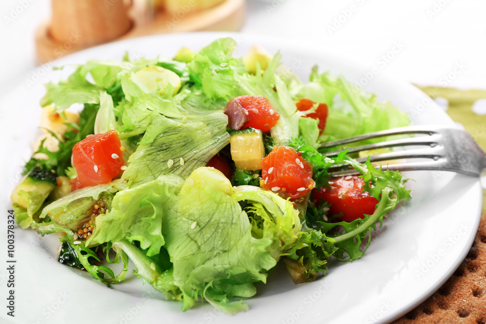 Tasty salmon salad on light wooden background