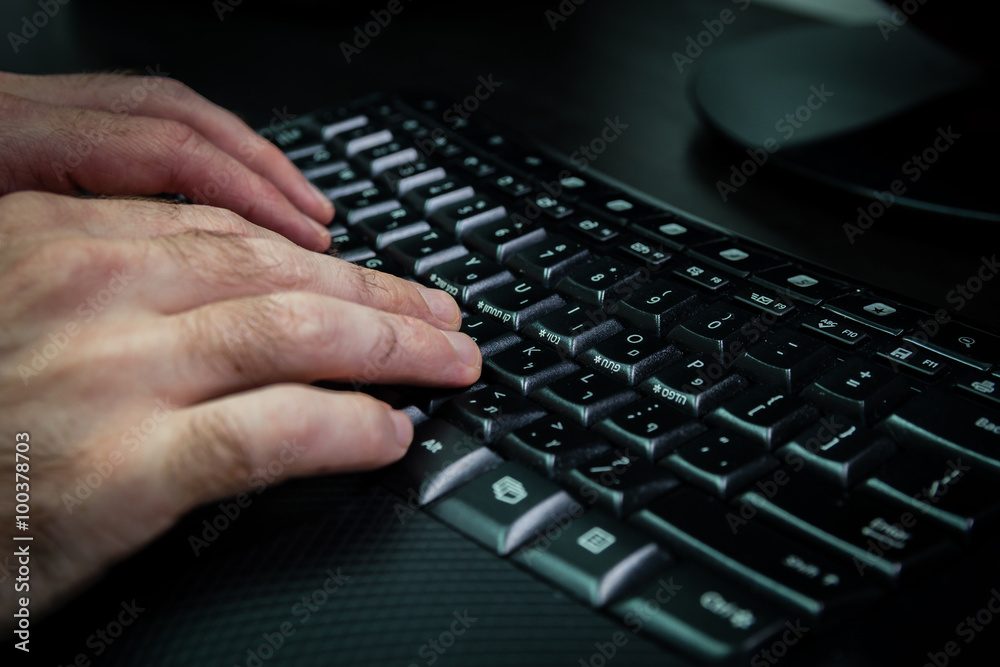 Man typing on a keyboard with letters in Hebrew and English - Wireless keyboard - Dark atmosphere Man typing on a keyboard with letters in Hebrew and English - Wireless keyboard - Dark atmosphere