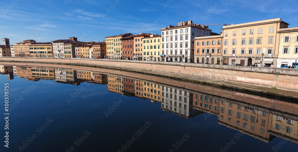 A view on the river Arno in city of Pisa, Italy, from Ponte di Mezzo towards Ponte di Solferino. Beautiful river bank panorama with reflection on the surface of the river. Wide photo format.
