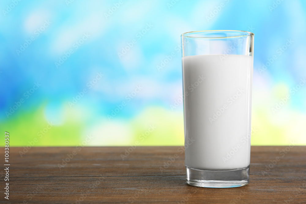 Glass of milk on table on blurred natural background Glass of milk on table on blurred natural background