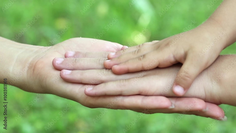 Female and childrens hands on grass background. Three hands together. Mother and daughters hands on green background. Concern for children. Hand in hand Female and childrens hands on grass background. Three hands together. Mother and daughters hands on green background. Concern for children. Hand in hand
