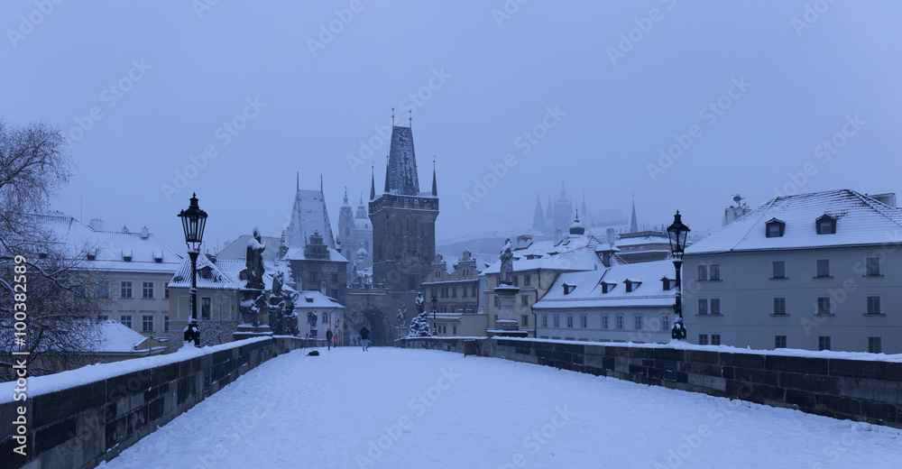 Early Morning snowy Prague Lesser Town  with gothic Castle, Bridge Tower and St. Nicholas' Cathedral from Charles Bridge with its Statues, Czech republic