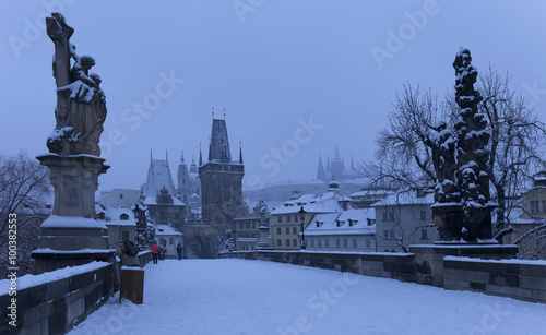 Early Morning snowy Prague Lesser Town with gothic Castle, Bridge Tower and St. Nicholas' Cathedral from Charles Bridge with its Statues, Czech republic