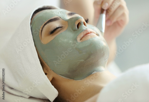 Spa concept. Young woman with nutrient facial mask in beauty salon, close up