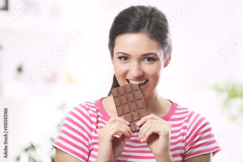 Portrait of beautiful young brunette with chocolate in the room , close up