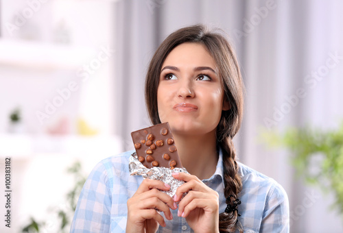 Portrait of beautiful young brunette with chocolate in the room   close up