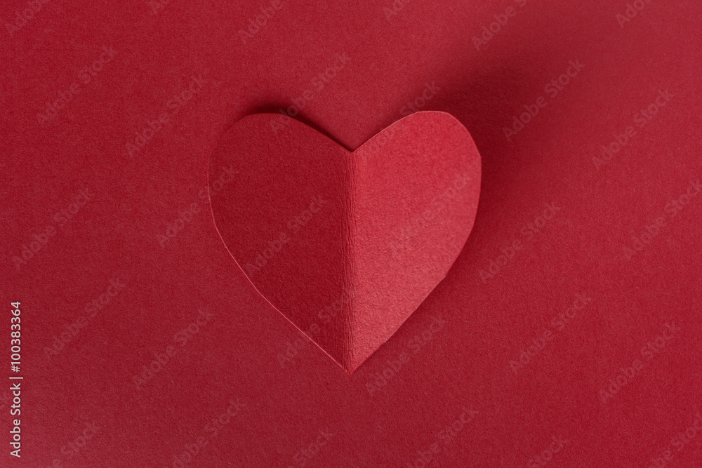 Red paper in heart shape on red background with shadow
