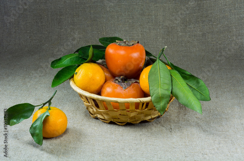 basket with tangerines and persimmons on sacking