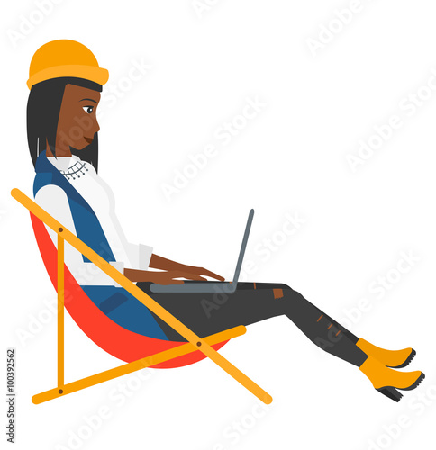 Business woman sitting in chaise lounge with laptop.