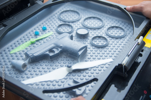 Black rubber rings, toy gun and small propellers lying on plastic bubble surface, print screen process