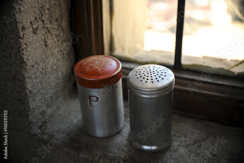 Salt and pepper shaker with red top on windowsill 