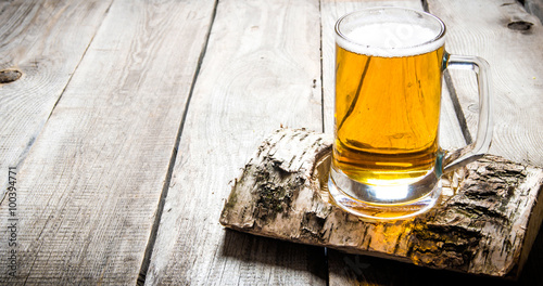 Εκτύπωση καμβά Glass of light beer on birch stand . On a wooden table.