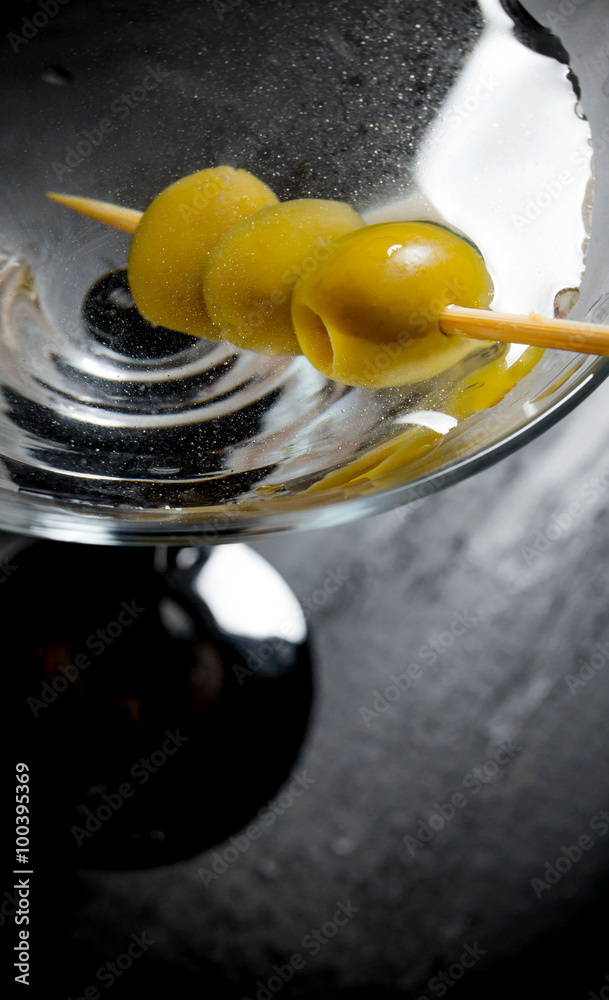 Martini with olives on a black table. Free space for text.