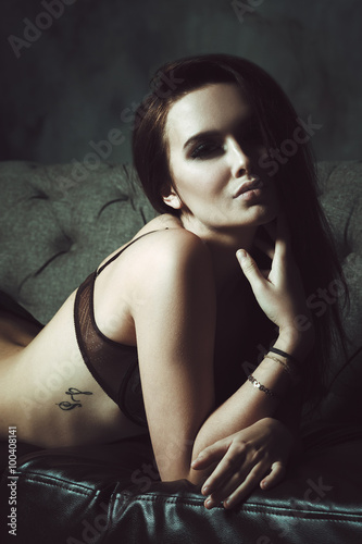 Young beautiful woman lying on leather sofa