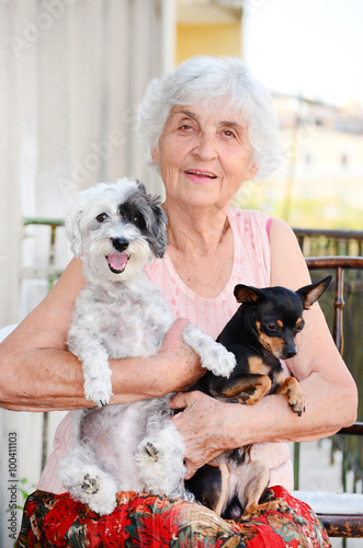 beautiful Senior smiling woman hugging two small dogs 