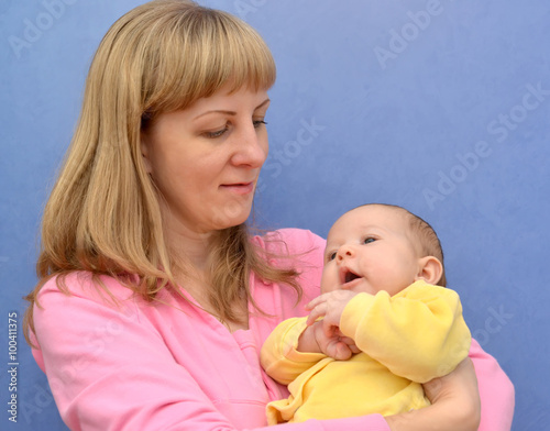 Portrait of the young woman with the baby on a blue background