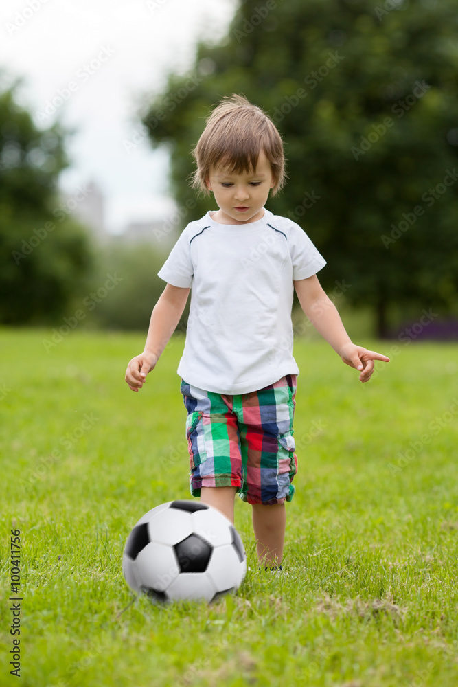 Cute little boy, playing football in the park Cute little boy, playing football in the park