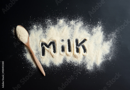Close up of powdered milk and spoon for baby on a black slate
