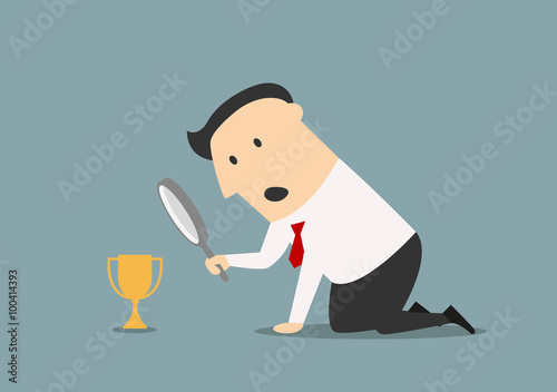 Businessman looking at trophy through magnifier