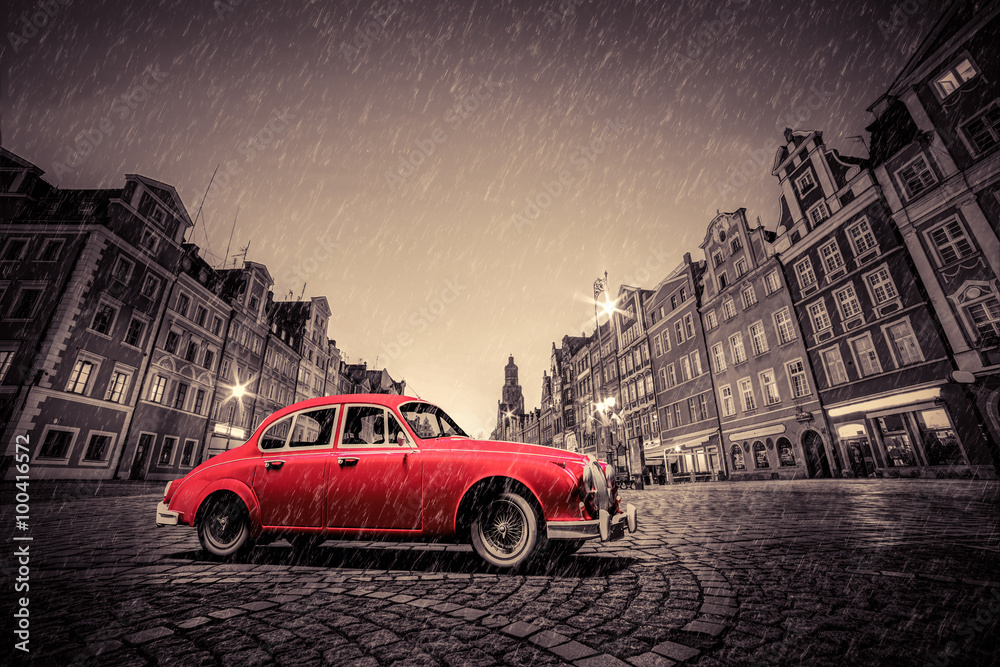 Retro red car on cobblestone historic old town in rain. Wroclaw, Poland.