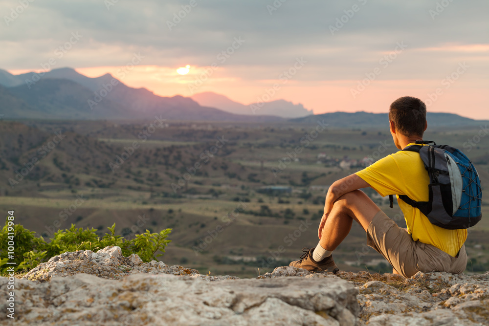 Naklejka premium Hiker with backpack sitting on a rock