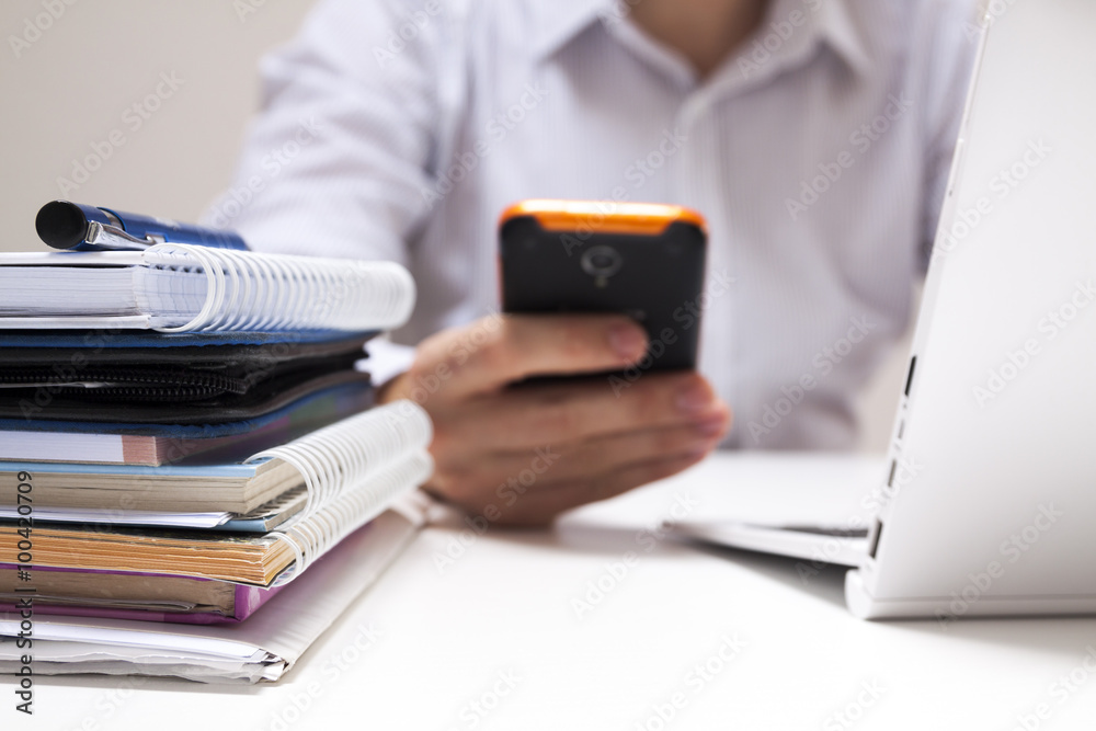 Fototapeta premium cell phone in business men's hand, working on laptop, in background in office