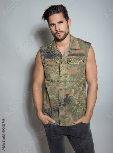 handsome young man in military jacket posing on grey backgorund