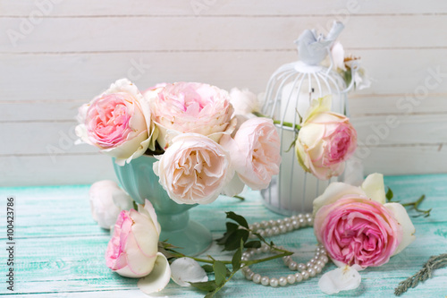 Pink roses and candle on turquoise painted wooden planks © daffodilred