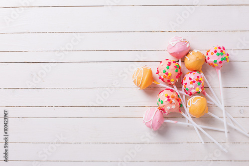 Cake pops on white painted wooden background.