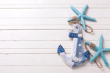 Decorative anchor and marine items on white wooden background.
