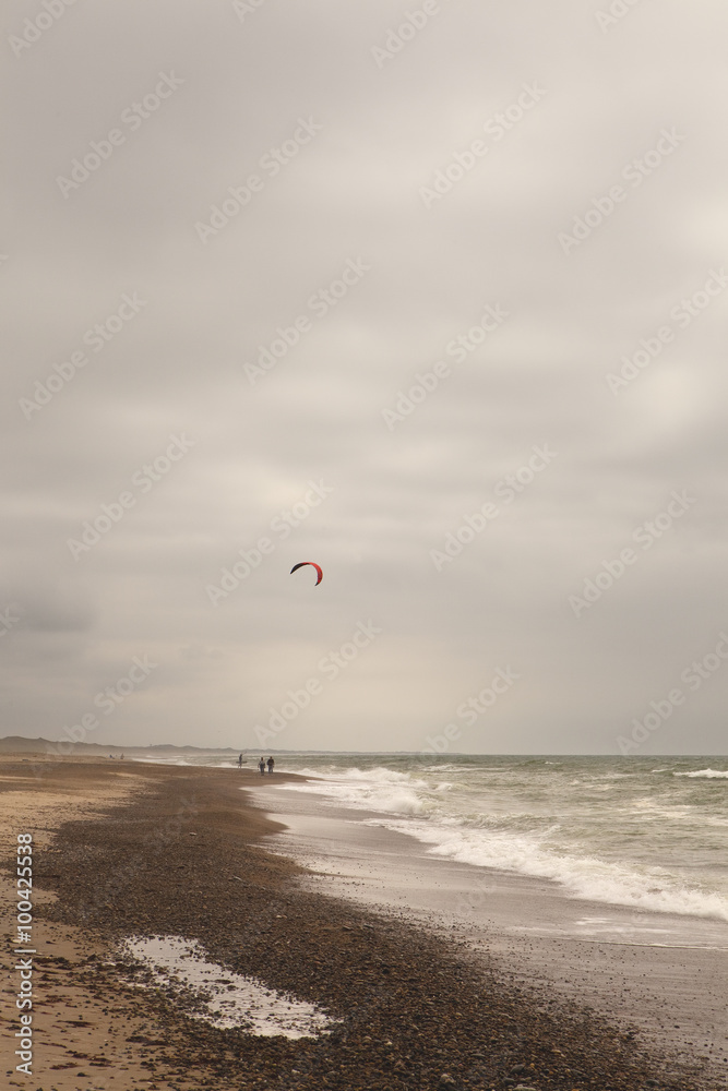 The Beach South of Klitmoller. A long straight beach, south of the town of Klitmoller, is where the kite surfers gather. A colourful kite brightens up an otherwise very stormy sky.