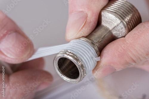 Plumber putting a teflon joint on a thread photo