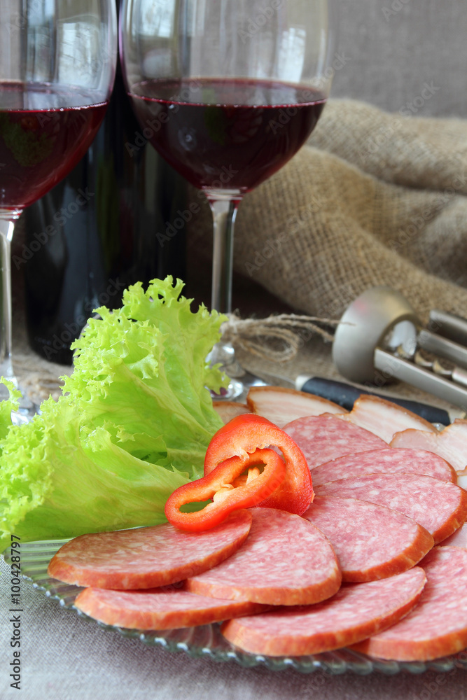 Two glasses of wine and a plate of sausages, decorated with lettuce.. Two glasses of wine and a plate of sausages, decorated with lettuce..
